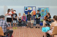 Foto der Klasse 3-4 bei ihrer Liedpräsentation (vergrößerte Bildansicht wird geöffnet)