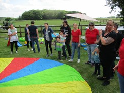 Frühförderinnen, Eltern und Kinder halten am Rand ein Schwungtuch fest.