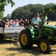 Foto von einem Traktor mit Anhänger gefüllt mit Kindern und Erwachsenen (vergrößerte Bildansicht wird geöffnet)