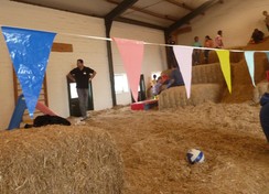 Foto: Blick in die Strohscheune mit gestapelten Strohballen und Personen darauf
