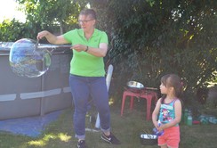 Foto von Frau Keller, die eine große Seifenblase formt, mit einem kleinen Mädchen