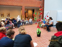 Foto: Die Schüler und Schülerinnen sitzen gemeinsam um den Apfel- und Birnenbaum und essen Kuchen und trinken Birnensaft.