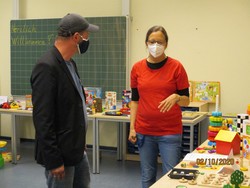 Foto einem Vater mit Frau Hemmers an Tischen mit verschiedenen Spielen (vergrößerte Bildansicht wird geöffnet)