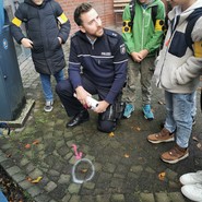 Foto der Gruppe mit Nikas beim Einsatz von Sprühkreide auf dem Boden (vergrößerte Bildansicht wird geöffnet)