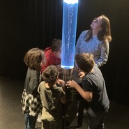 Foto von einer Lehrerin und Schüler:innen an einer Wassersäule mit Strudel (vergrößerte Bildansicht wird geöffnet)