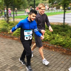 Foto von einem blinen Schüler mit Begleitläufer (vergrößerte Bildansicht wird geöffnet)