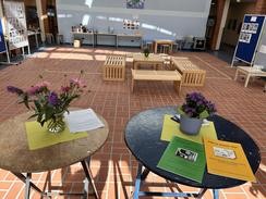 Blick in die helle Aula der Irisschule mit Sitzgruppen und Tischen mit Informationsmaterial.