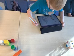 Ein Schüler sitzt vor seinem iPad auf dem er mit seinem Apple Pencil eine Stadt zeichnet.