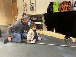 Foto von Juan und Luise auf dem Boden mit Langstock und einer großen Dose