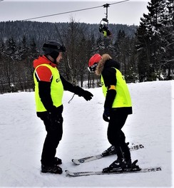 Foto von einem Skilehrer, der rückwärts vor einem skifahrendem Schüler läuft