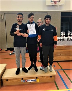 Foto von Arshat, Lennart, Mohanad und Mohamed auf dem Siegertreppchen mit Pokal und Urkunde
