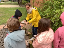 Foto von Frau Altholtmann mit einer Kindergruppe und durchlöcherten Holzstücken