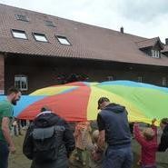 Foto: Schwungtuch senkt sich und bedeckt einige Kinder (vergrößerte Bildansicht wird geöffnet)