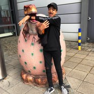 Foto von Mohamed mit einem Arm im Maul eines schlüpfenden Dinos (vergrößerte Bildansicht wird geöffnet)