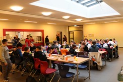 Foto verschiedener Mannschaften und Betreuer:innen im Speiseraum der OGS