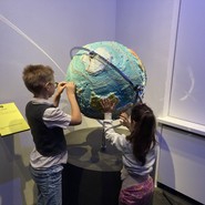 Foto von Alexandra und Ragnar beim Ertasten eines großen tastbaren Globus (vergrößerte Bildansicht wird geöffnet)
