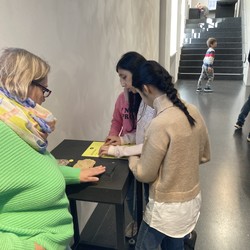 Foto von Schüler:innen an einer Punktschrifttafel (vergrößerte Bildansicht wird geöffnet)