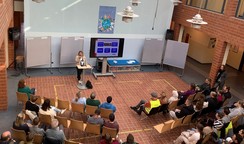 Foto: Schulleiterin Elisabeth Hordt steht mit Mikro in der Aula vor den versammelten Eltern.
