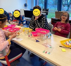 Foto: Zwei Kinder der Klasse gestalten mit Eltern und Großeltern weihnachtliche Windlichter
