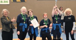 Foto: Die Mädchen stehen nach der Gratulation der Trainer und der Schulleitung von der Louis Braille Schule in Düren ( Frau Grün-Klingebiel) zur Siegerehrung beieinander und halten den Pokal in die Luft.