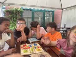 Foto mit Kindern am Tisch mit Mensch-Ärgere-Dich-Nicht-Spiel