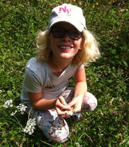 Foto einer Schülerin in einer Blumenwiese (vergrößerte Bildansicht wird geöffnet)