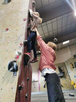 Foto von Mathilda an der Boulderwand. Sie wird von Frau Friemann unterstützt. (vergrößerte Bildansicht wird geöffnet)