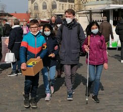 Foto von Schüler:innen mit einem Praktikanten mit Spendenbox auf dem Wochenmarkt