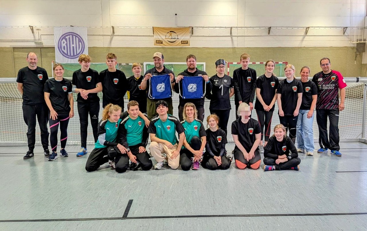 Alle Spieler:innen und Trainer:innen stehen zusammen für ein Abschlussfoto vor einem Goalballtor.