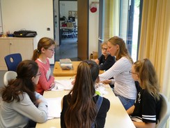 Foto der Teilnehmer mit Frau Neubauer am Tisch mit ihren weißen Kleidungsstücken