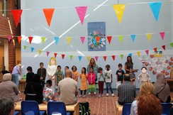 Foto der Schüler:innen und Lehrer:innen der Primarstufenklassen beim Singen vor dem Publikum
