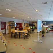 Foto eines großen Raumes mit Stellwänden, Zeitschriftnregal und aufgeklebten roten Fußspuren auf dem Boden (vergrößerte Bildansicht wird geöffnet)