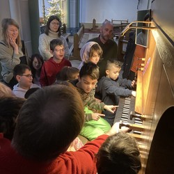 Foto der Gruppe  mit ihren Betreuer:innen an der Orgel (vergrößerte Bildansicht wird geöffnet)