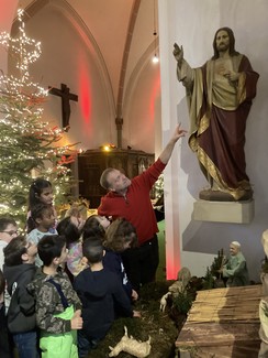 Foto der Gruppe mit Herrn Schubert in der Kirche an der Herz-Jesu-Figur