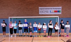 Foto der Vertreter der 10 teilnehmenden Schulen mit einem Schild der jeweiligen Schule