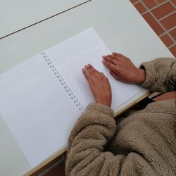 Foto von Vida beim Lesesn ihres Punktschriftbuches (vergrößerte Bildansicht wird geöffnet)
