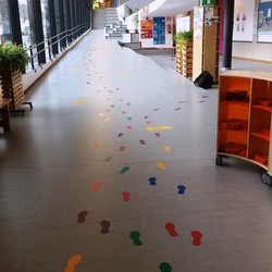 Foto des Flurs mit aufgeklebten verschiedenfarbigen Fußabdrücken (vergrößerte Bildansicht wird geöffnet)
