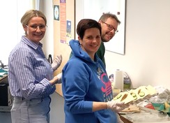 Foto: Die Elternvertreter:innen und Ehepartner bereiten Schnittchen vor. Im Vordergrund l. Frau Vollmerhaus, r. Frau Sutholt; im Hintergrund Herr Vollmerhaus