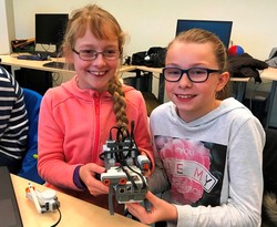 Foto von zwei Schülerinnen mit ihrem Roboter (vergrößerte Bildansicht wird geöffnet)