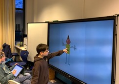 Foto: Schüler sitzen vor dem WhiteBoard und schauen die erstellten Kunstwerke an.