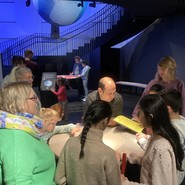 Foto von Lehrer:innen und Schüler:innen am Modell eines Meteoriteneinschlags (vergrößerte Bildansicht wird geöffnet)