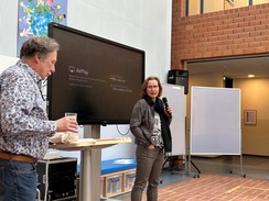 Foto: Frau Böttcher und Herr Posingies, der stellvertretende Schulleiter, stehen in der Aula. Frau Böttcher spricht in ein Mikro und hält einen Vortrag.