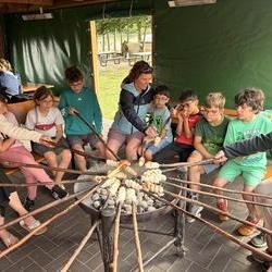 Foto: Kinder und Erwachsene mit ihren Stockbrotstöcken um eine Feuerschale (vergrößerte Bildansicht wird geöffnet)
