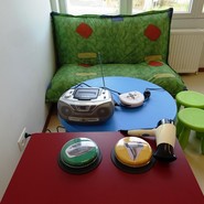 Foto eines Raums mit Sitzkissen Tischen und verschiedenen Tastern zum Starten von Geräten (vergrößerte Bildansicht wird geöffnet)